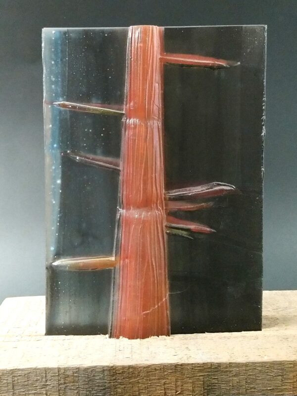 szklana rzeźba "Czerwony bambus" na drewnianej podstawie- zbliżenie, w podstawie ukryte źródło światła, babus reliefowy czerwono-pomarańczowy, tło czarne